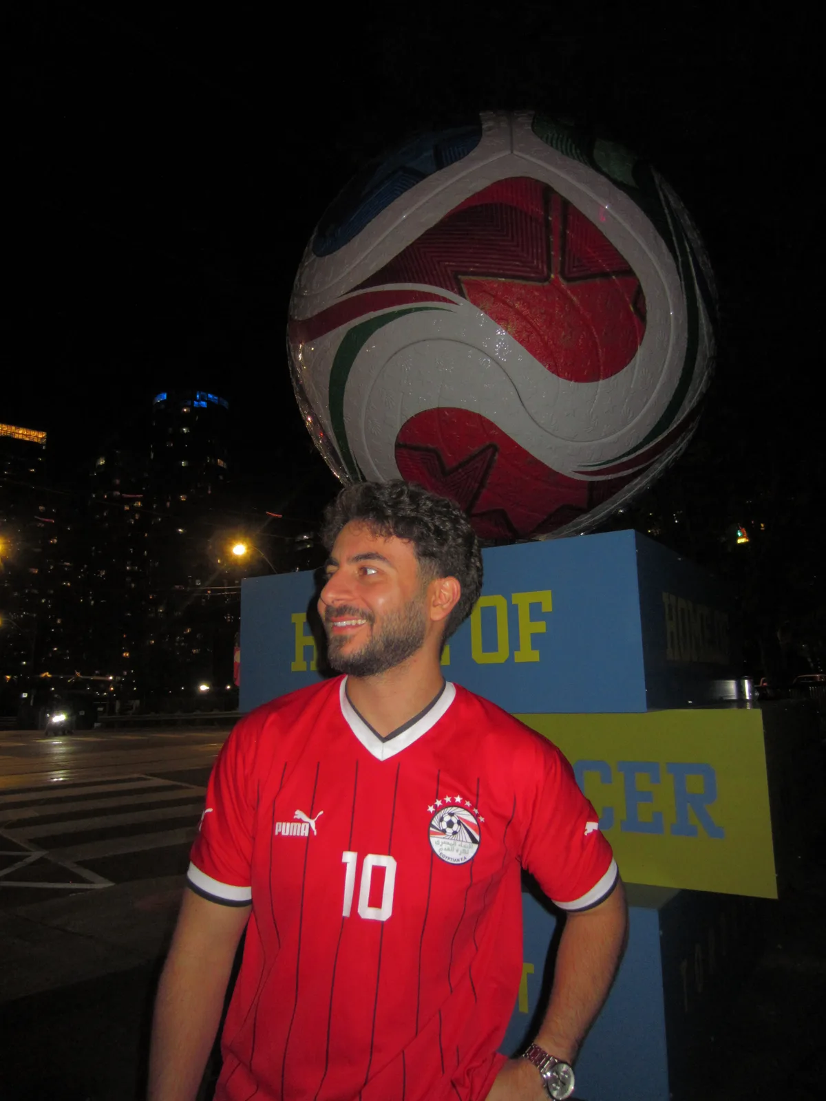 Wearing an Egypt number 10 shirt beside a giant football sculpture at night